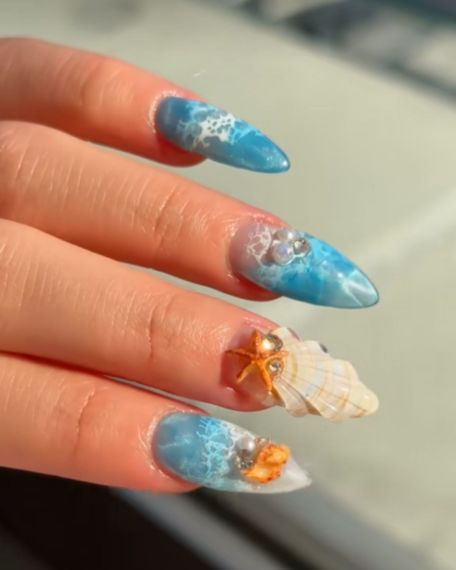 Ocean theme nail art with waves, seashells, and starfish