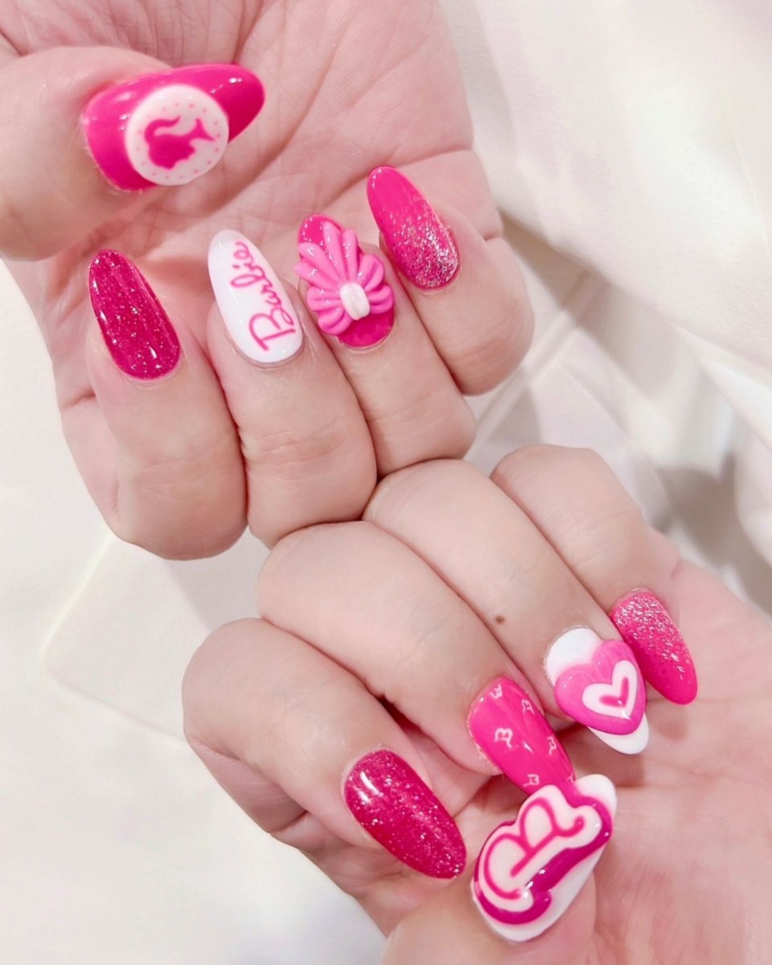 Pink gel nail art in Barbie theme decorated with 3D raised hearts
