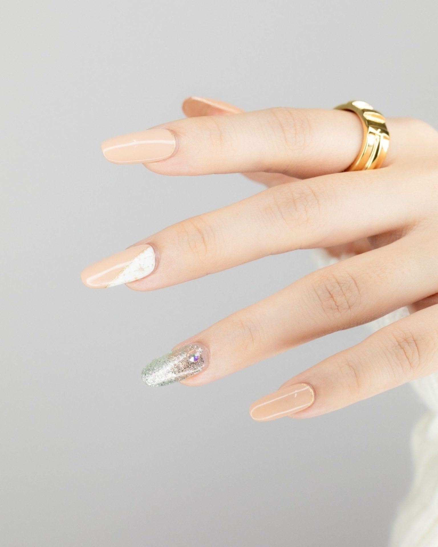 Elegant nude tone nail art with glitter and crystals