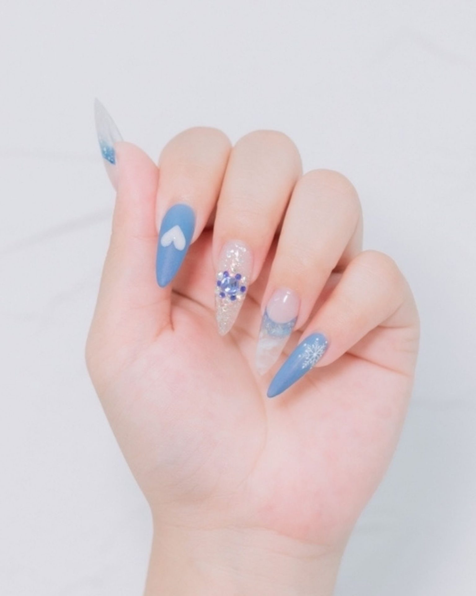 Blue toned nail art decorated with snowflake and heart design