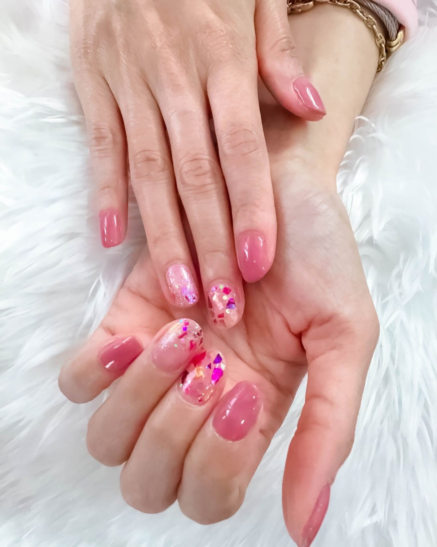 Short round nails in sweet pink decorated with holographic glitter sheets for a bright, standout look