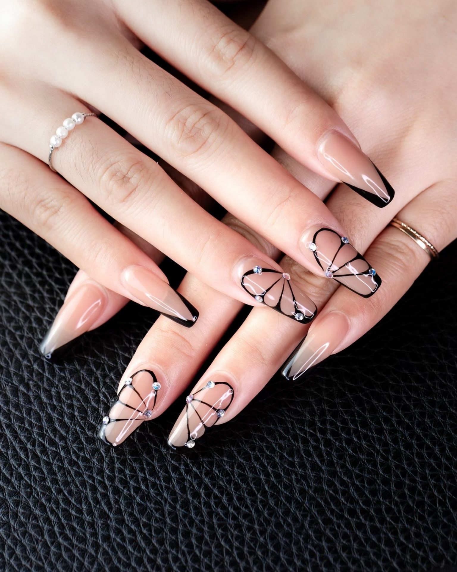 Long nails painted with black butterfly wing design decorated with crystals
