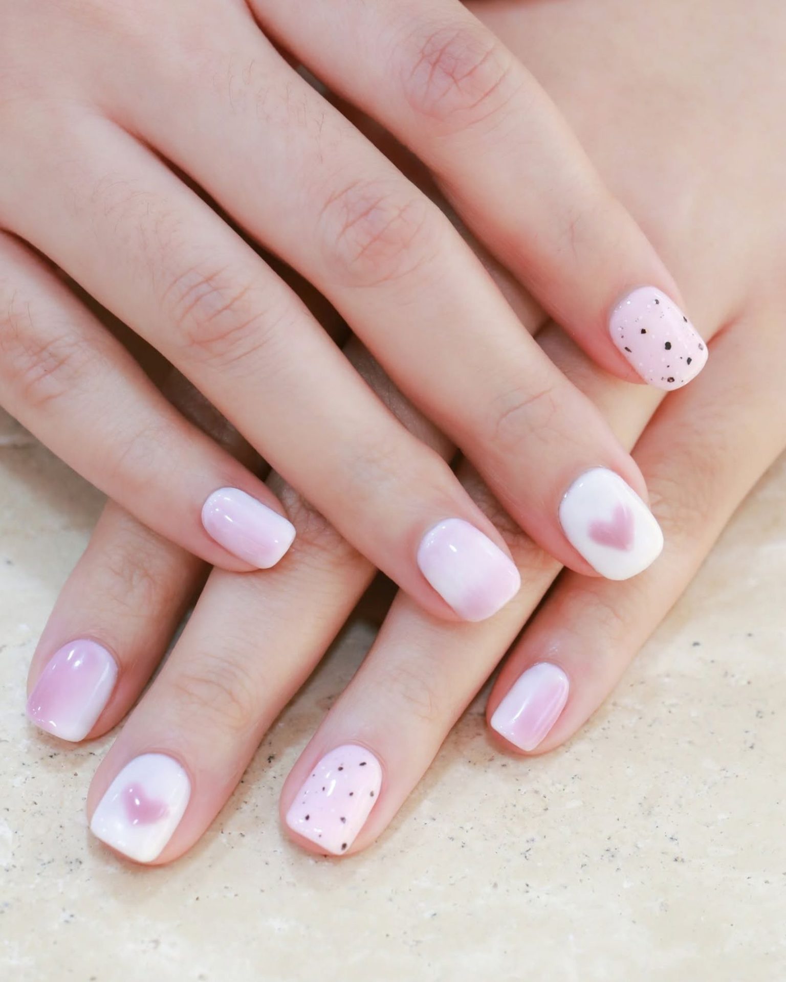 Short nails with light pink ombre, painted with hearts and small black dots, cute minimalist style