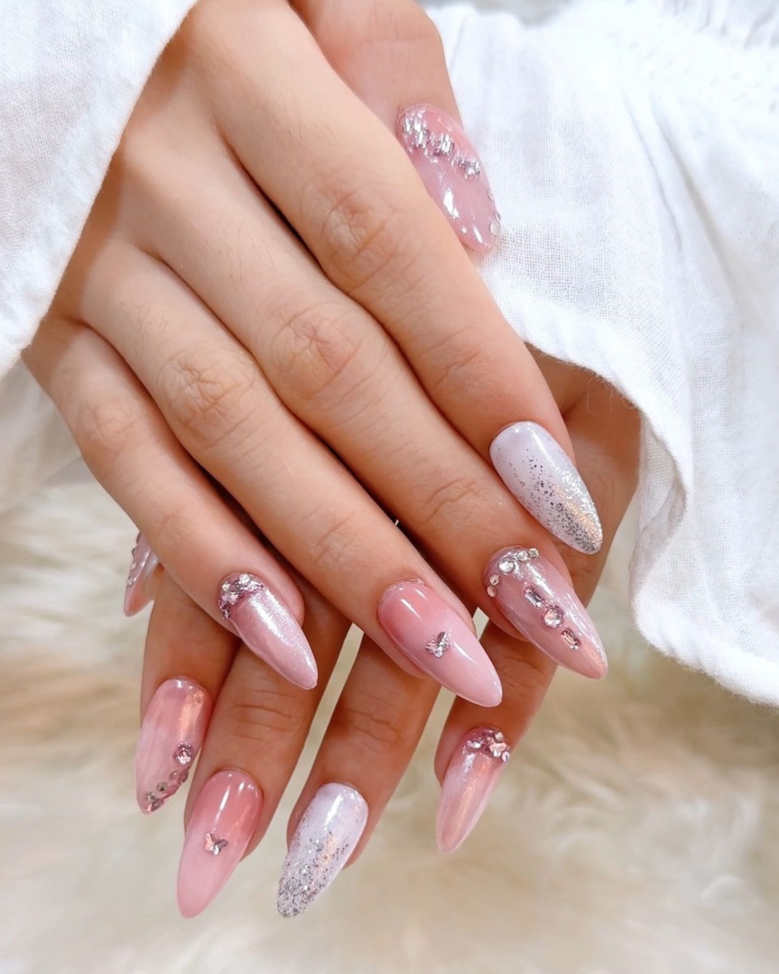Almond-shaped nails with pink gradient decorated with rhinestones and glitter