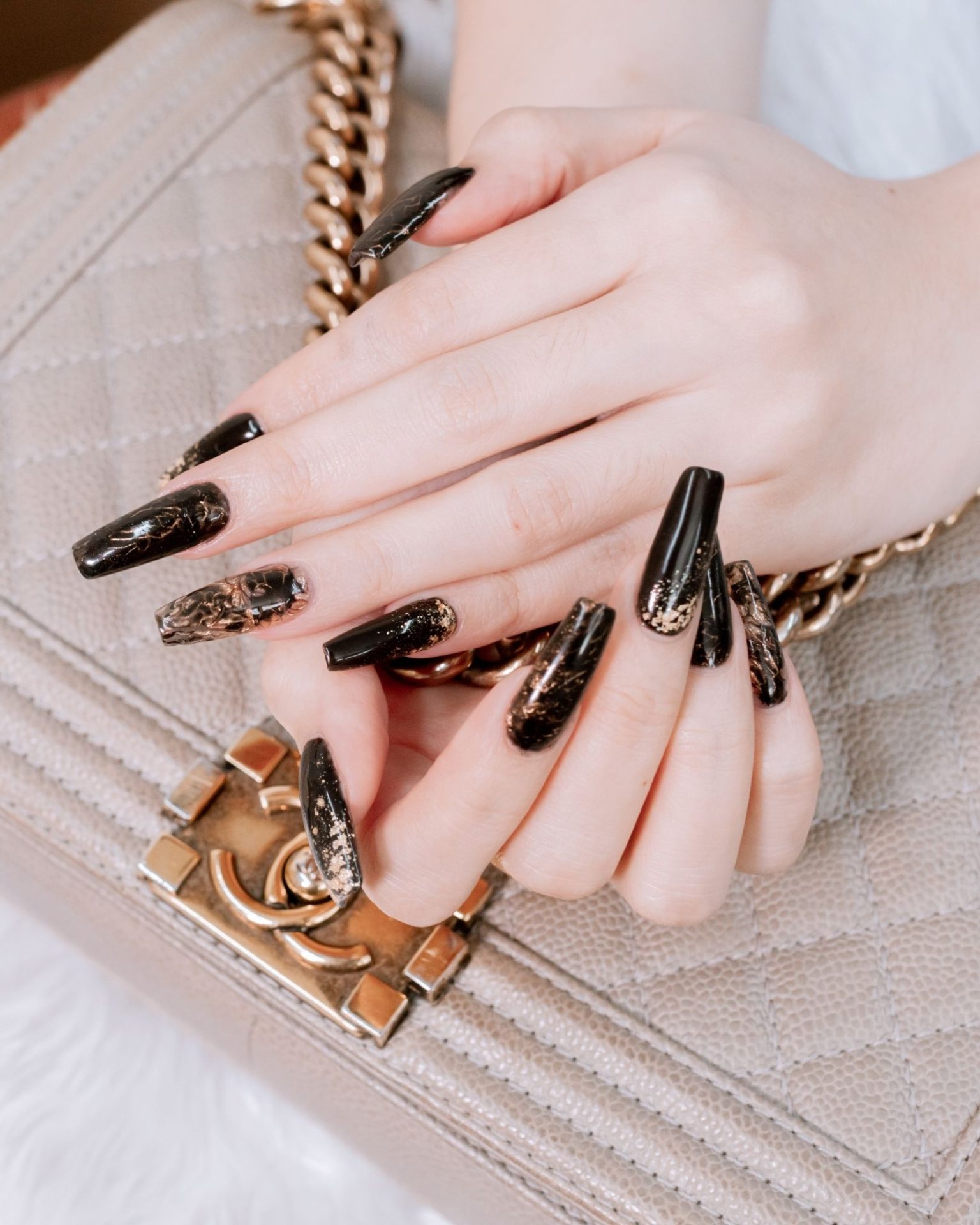 Long stiletto nails in black with gold marble pattern for a luxurious, bold, modern feel