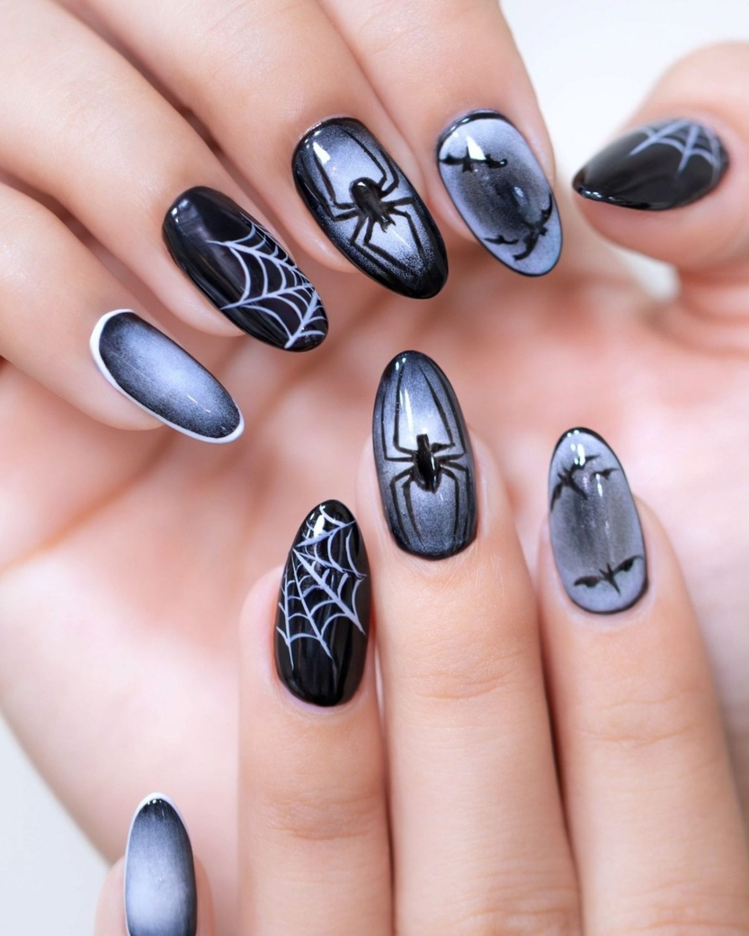 Halloween-theme nail art painted with spiderweb and bats in gray-black tone