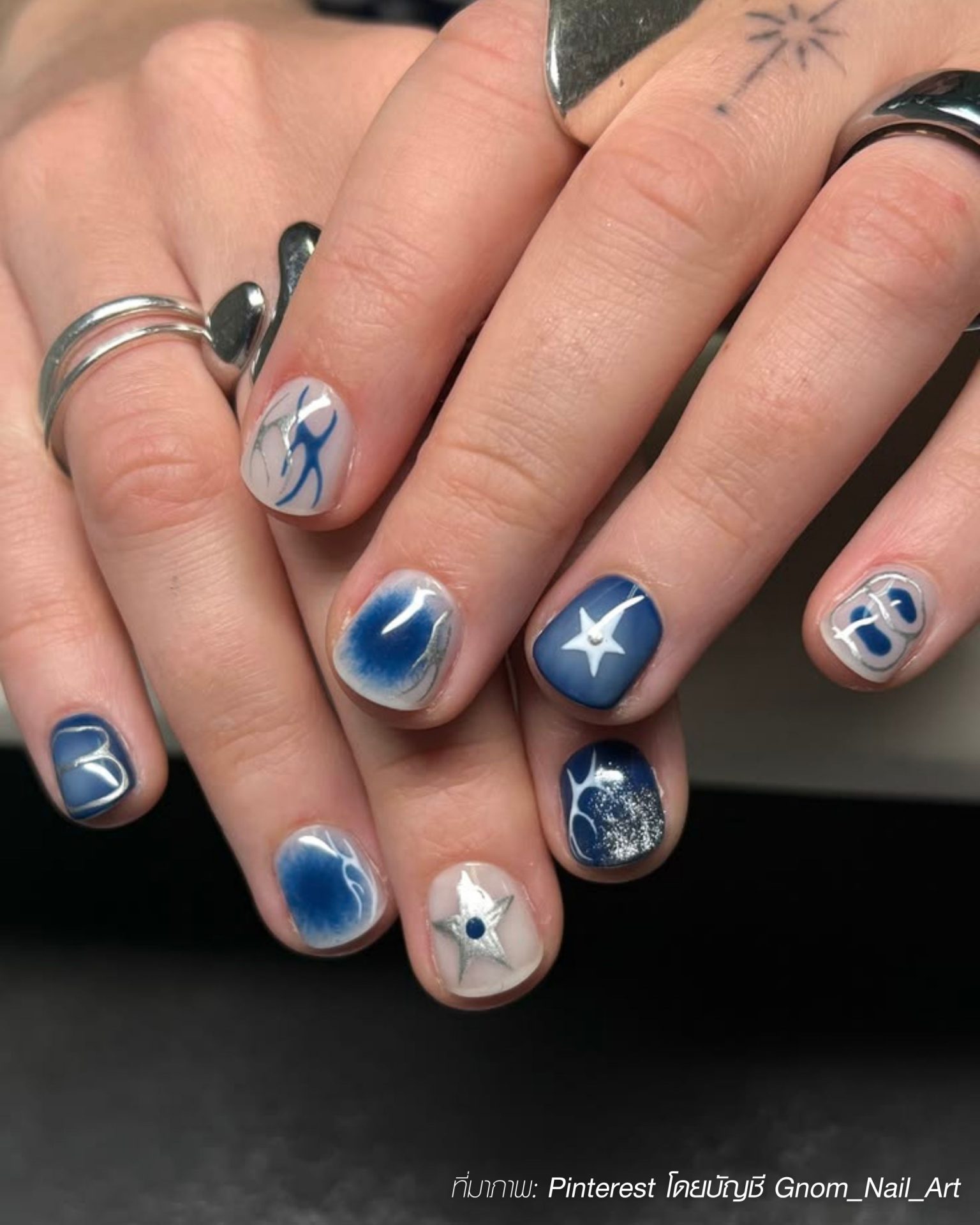Cool artwork designs on men's nails with navy blue and silver stars and spirals