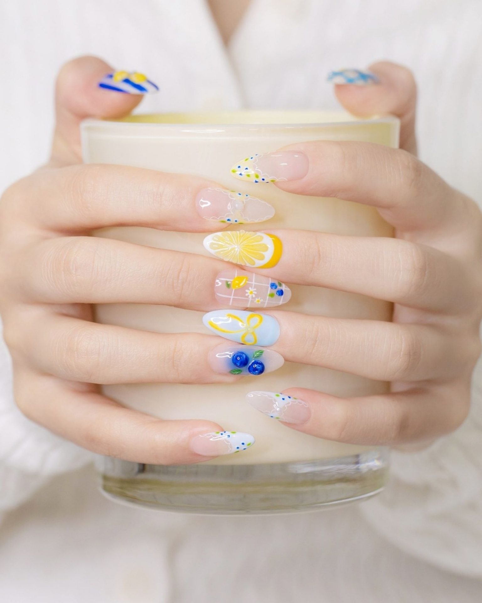Adorable fruit nail art painted with lemon, flowers, and blueberries on a clear base, summer style