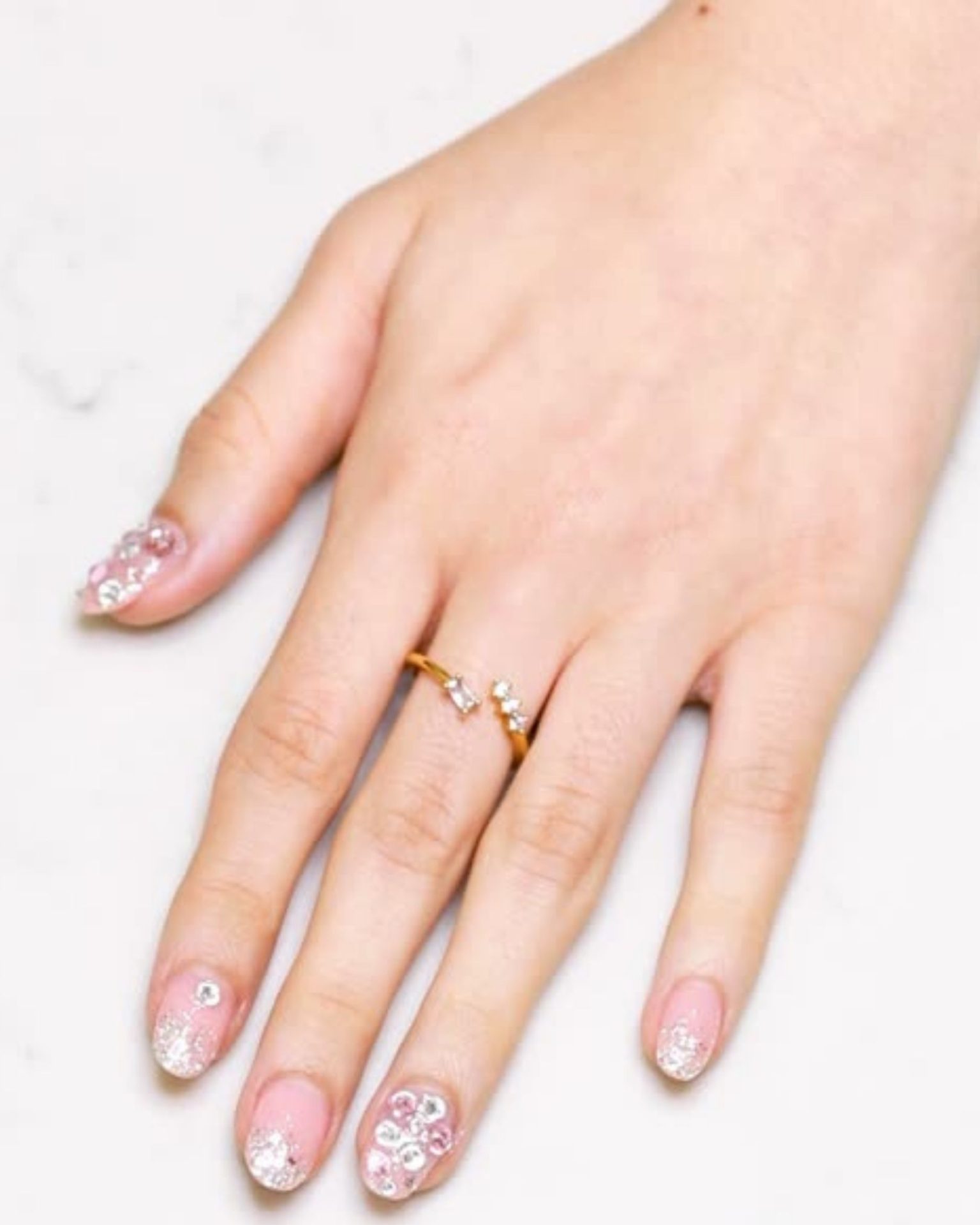 Short nude toned nails decorated with glitter and rhinestones