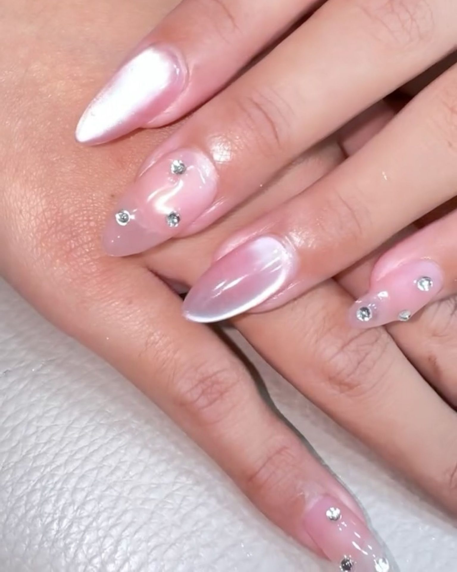 Milky pink Cat Eye shine nails decorated with small crystals for extra sparkle