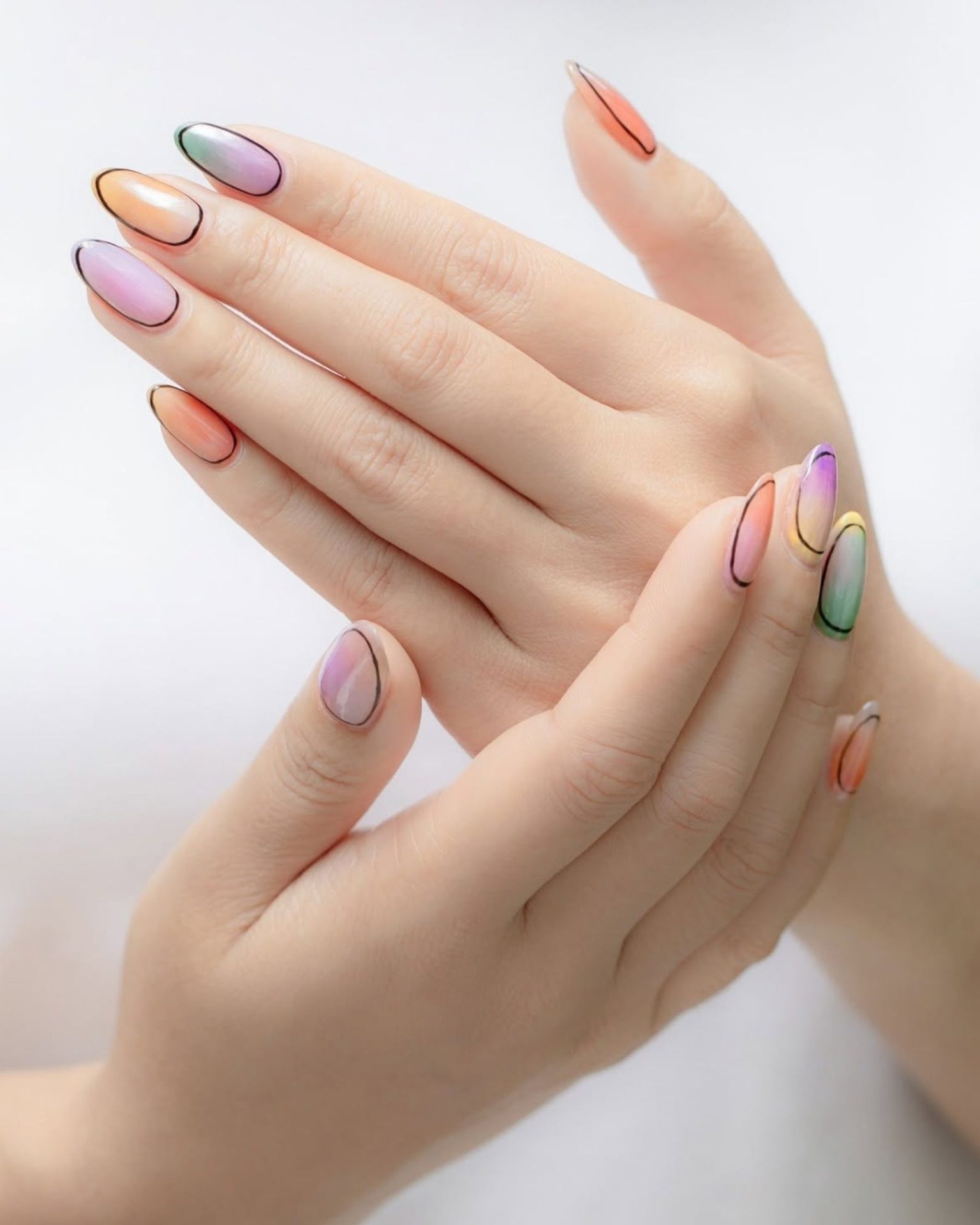Light pastel ombre nails decorated with black outline around the nail, minimalist style
