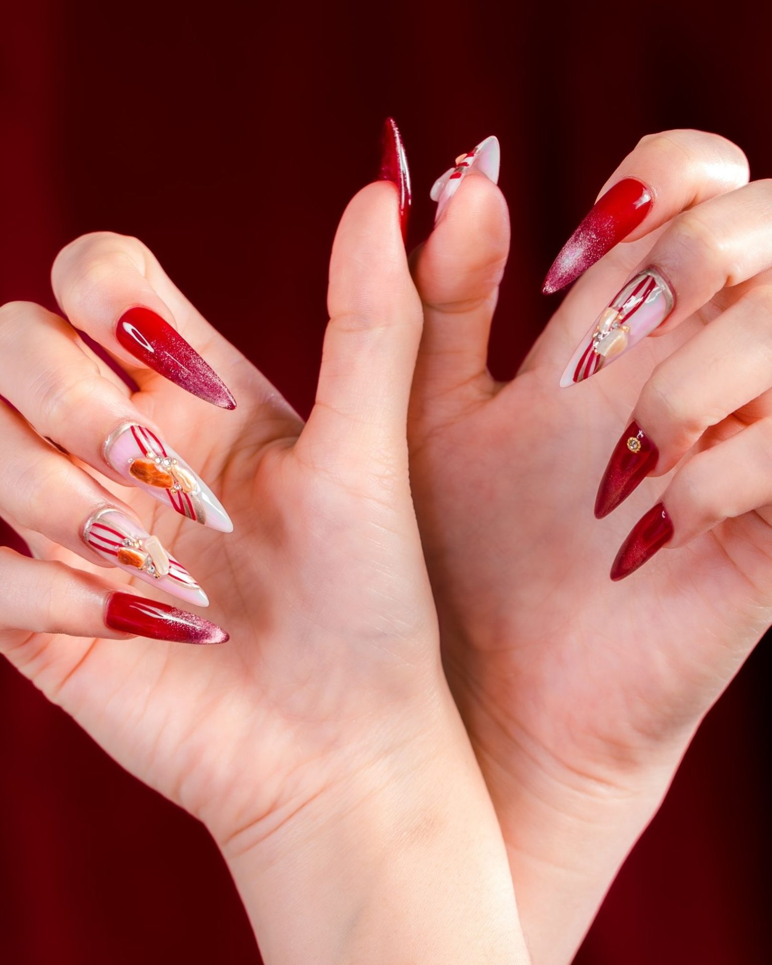 Deep red ombre gradient nails painted with Christmas design decorated with luxurious crystals