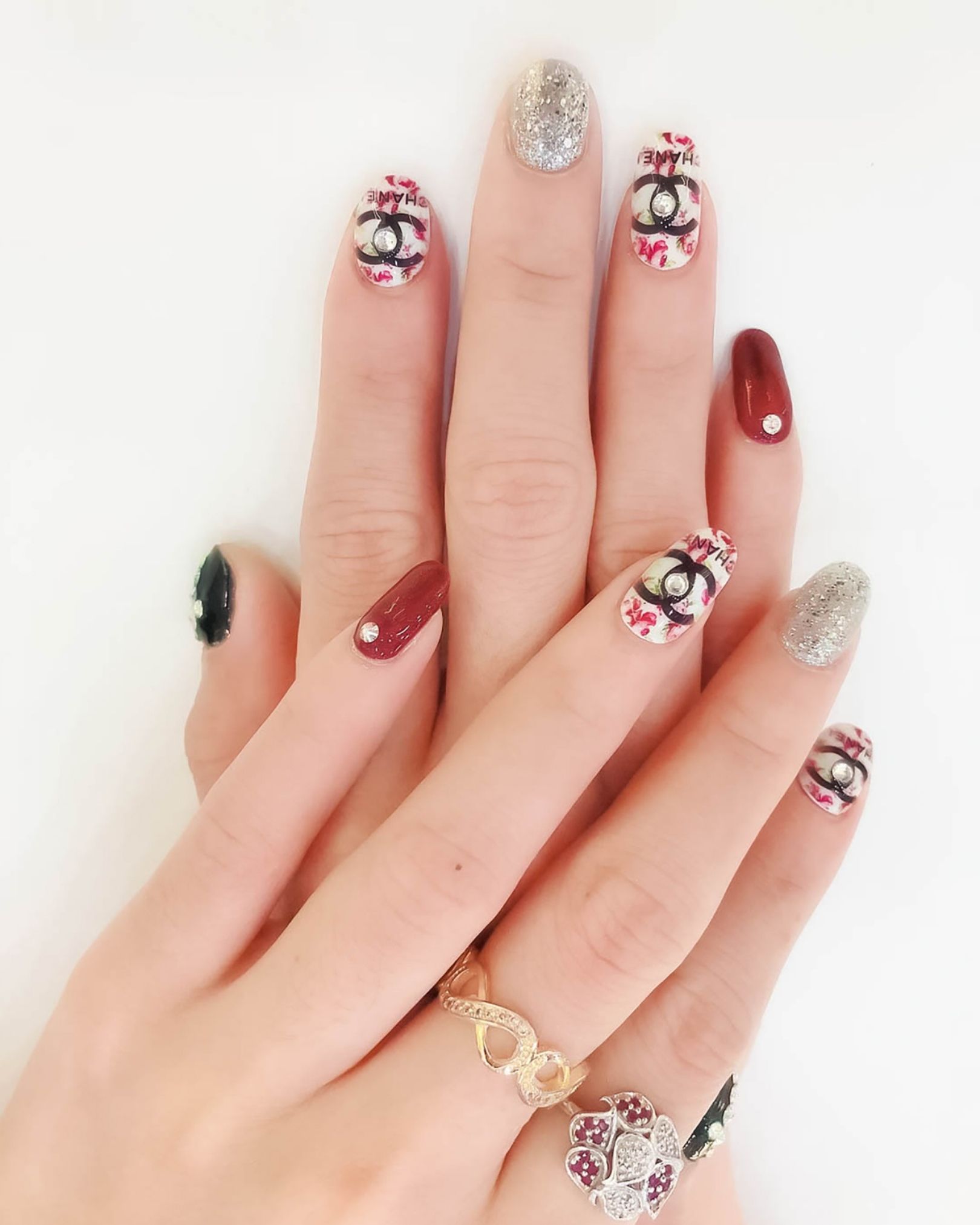 Floral and designer-logo nail art decorated with glitter and crystals in high-end fashion style