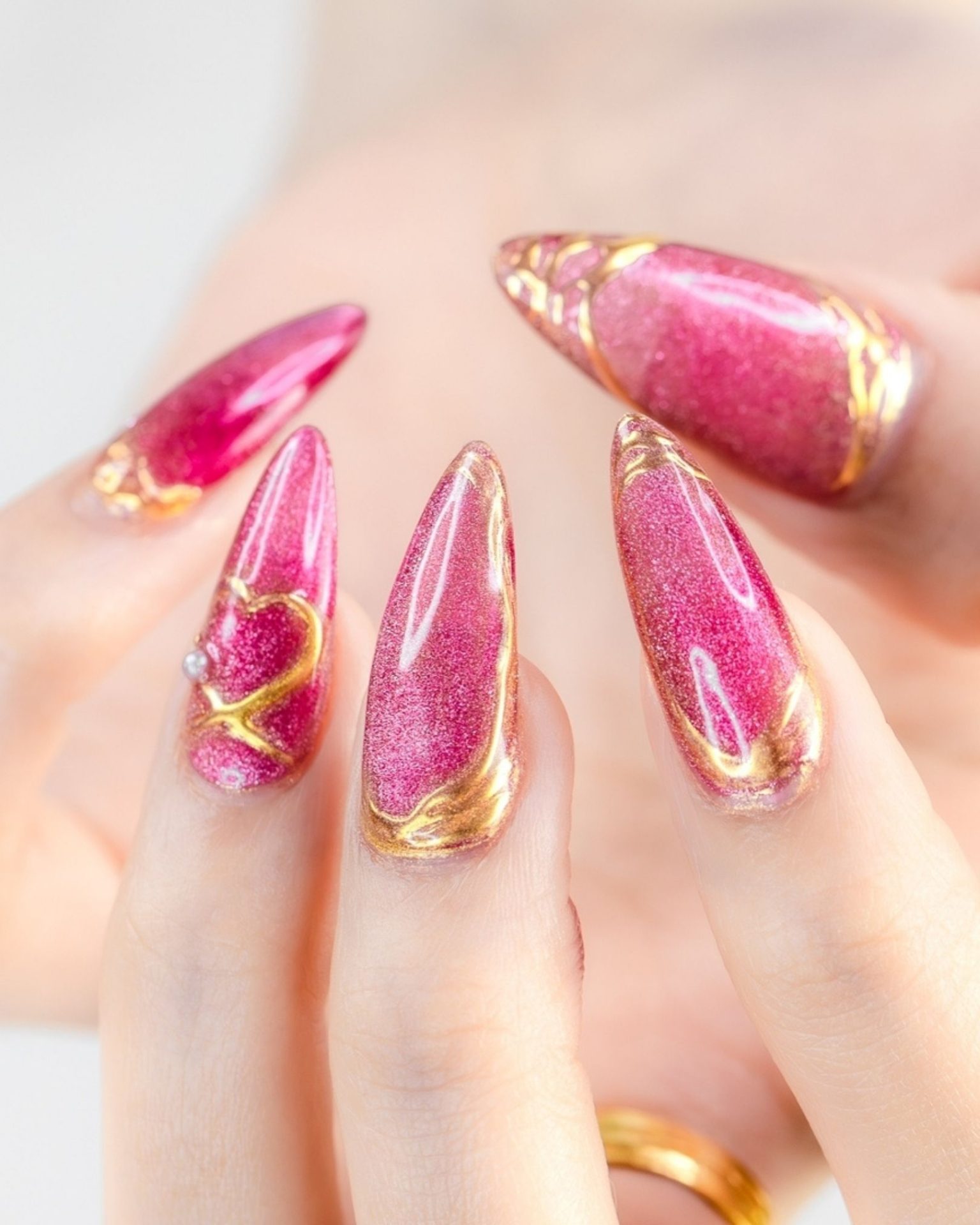 Gold heart nail art on sand-textured pink background