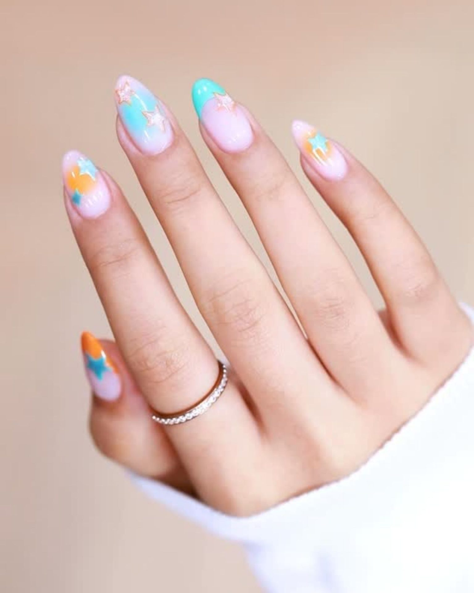 French tip nails in bright color decorated with orange and pastel blue star patterns