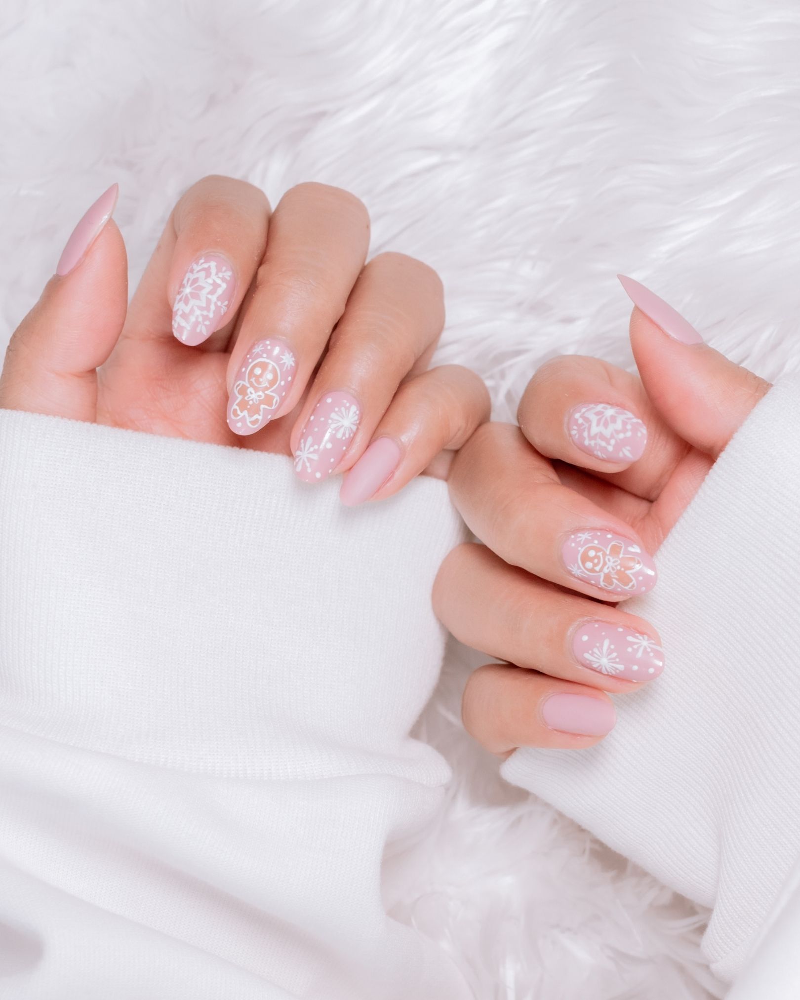 Soft pink toned nails painted with gingerbread cookie and snowflake design, cute Christmas style