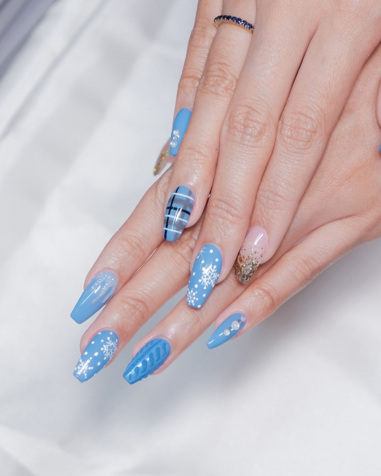 Blue toned nails with plaid and snowflake pattern, winter design decorated with crystals