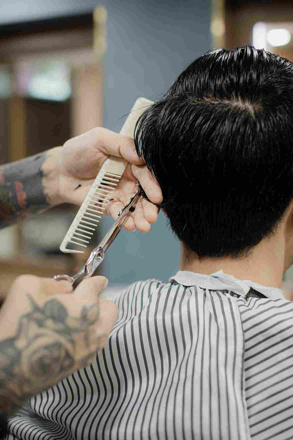 Barber cutting a man's hair with scissors at One Man Club, Sukhumvit 35, Bangkok
